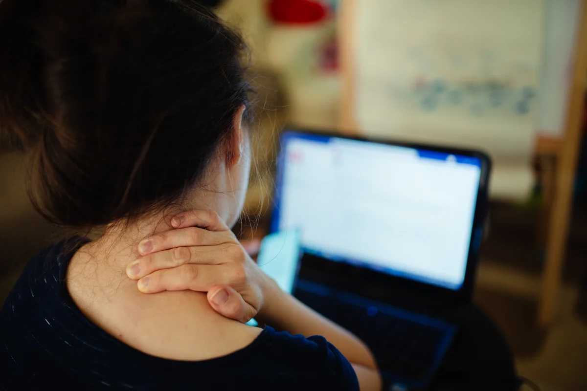 Woman with neck pain at her laptop — chiropractic care can help relieve it